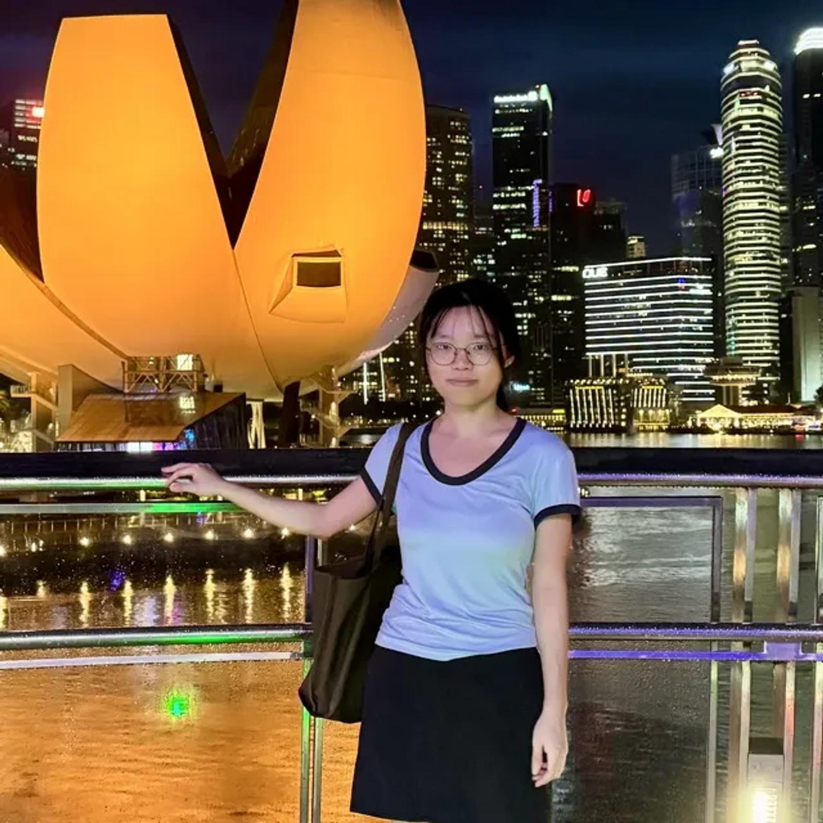 Yufei Wang in front of the ArtScience Museum and the Marina Bay skyline in Singapore at night