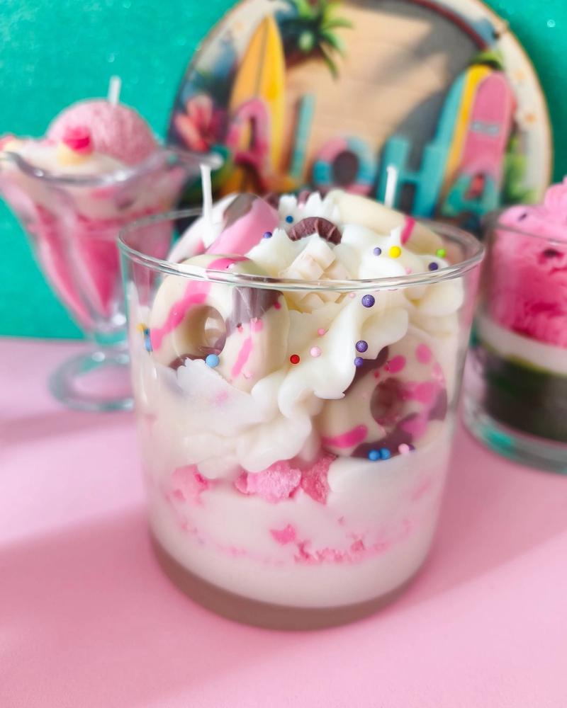 Nuestro tanque de cera - Crema montada con olor a chocolate blanco, galleta de color rosa con un toque a fresa y adornos de roscas y tabletas de chocolate con aroma a choco. En vaso de cristal.