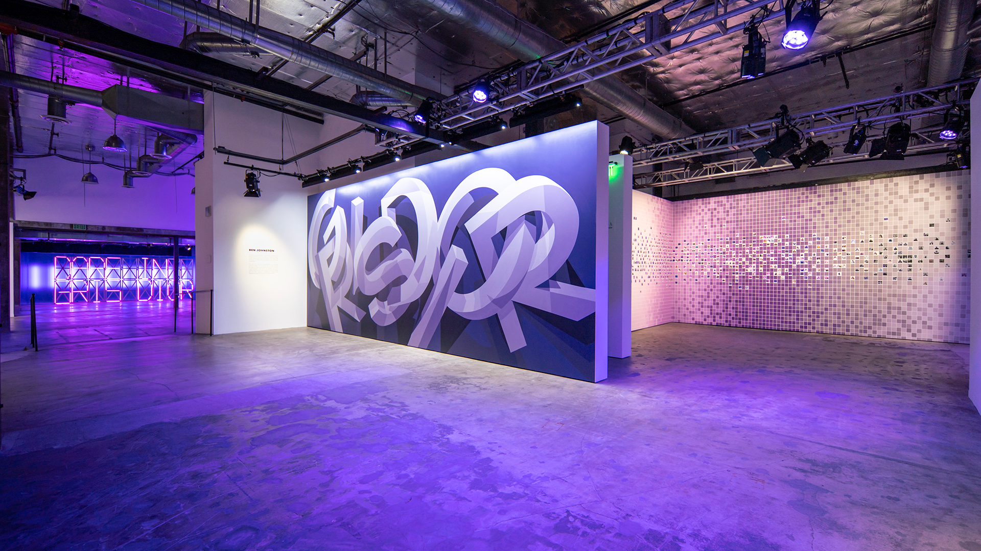 Three-room view of Dior Grey Zone exhibition in Los Angeles featuring a Gris Dior logo mural by Ben Johnston, a purple neon “Dare in Gris Dior” installation, and a photo mosaic wall.