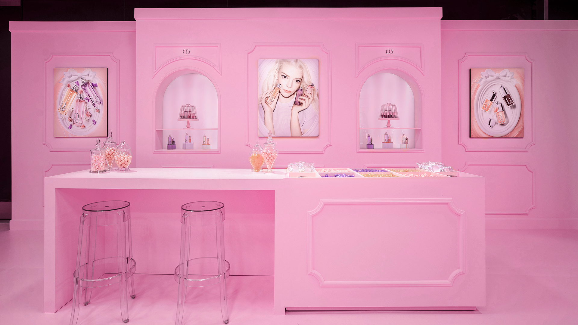 Pink table for filling candy bags with product displays in wall alcoves at the Dior Sweet pop-up in Los Angeles.