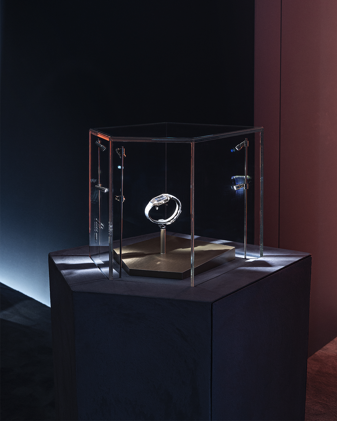 Close-up of a single Audemars Piguet watch displayed in a glass vitrine inside a dark blue immersive room with gold details.