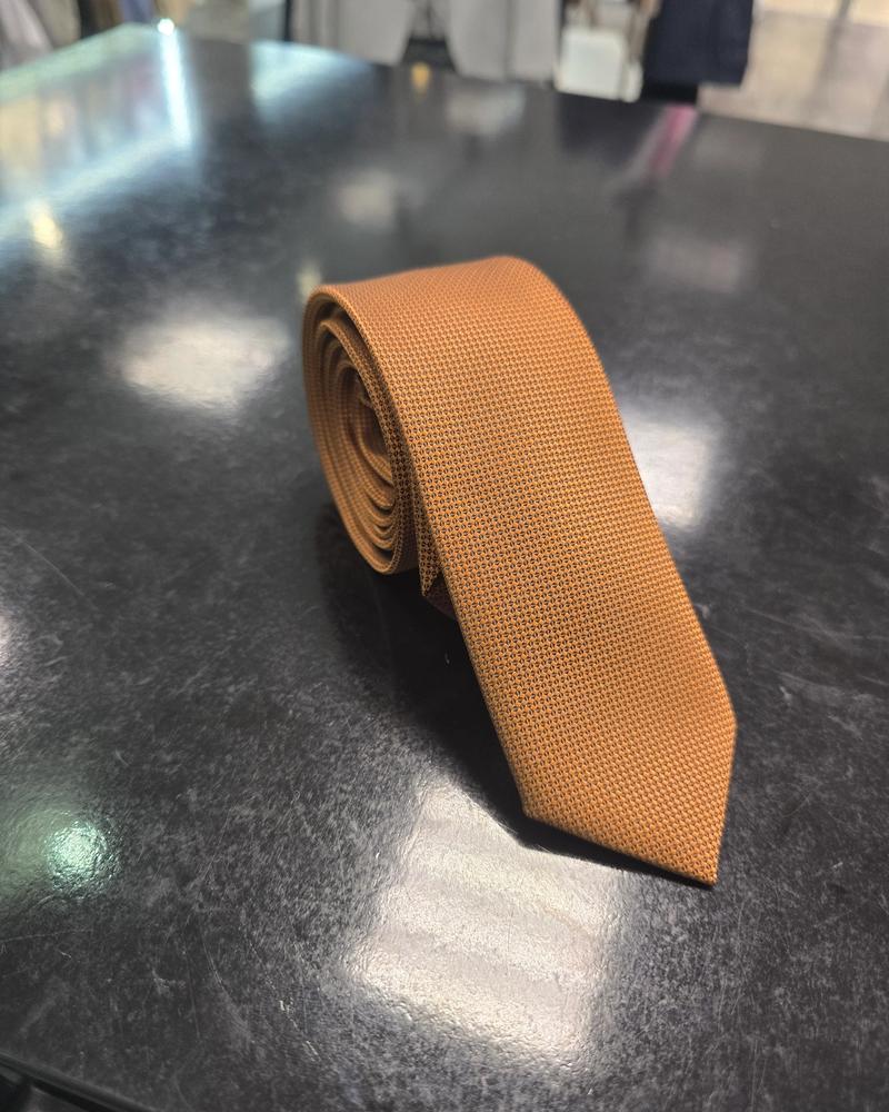 Viento textured burnt orange tie, vertical full-length view on dark counter
