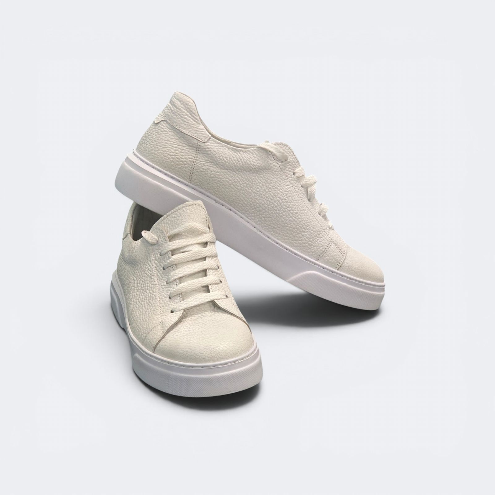 Viento cream leather sneakers as a pair, three-quarter front, one resting on the other.