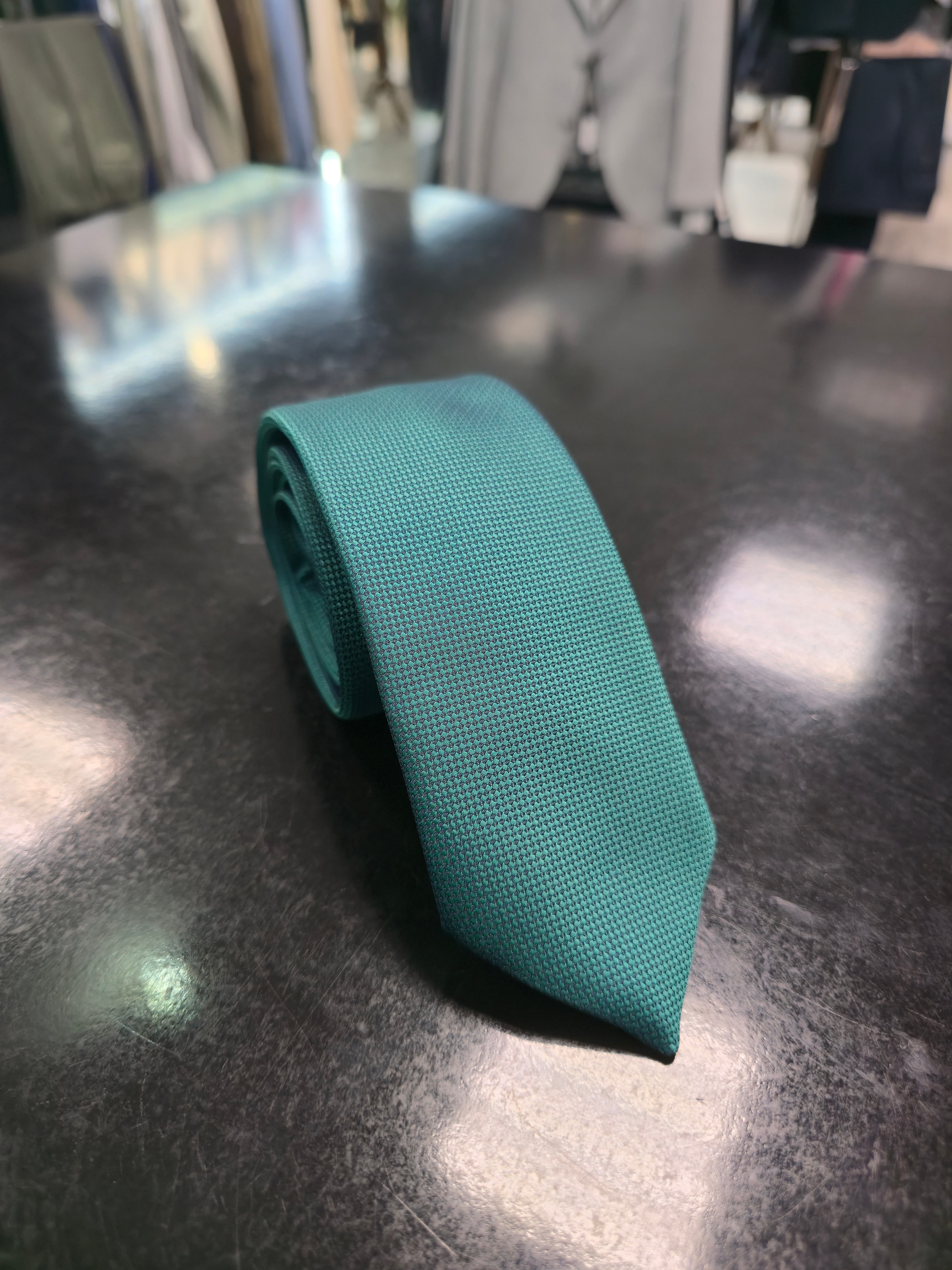 Viento textured teal green tie, full length on dark counter