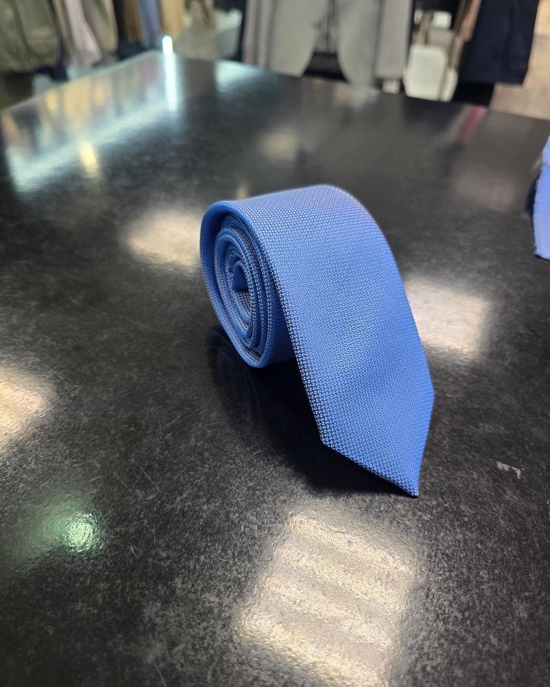 Viento textured cornflower blue tie, vertical full-length view on dark counter