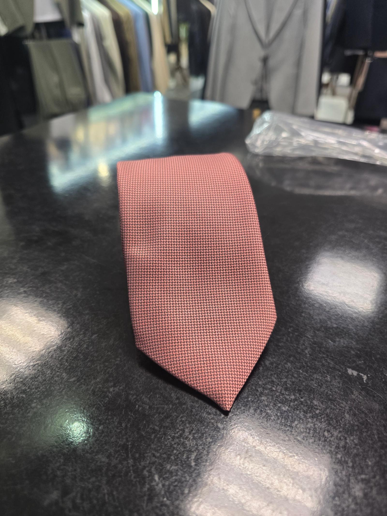 Viento powder pink textured tie, rolled view on dark counter