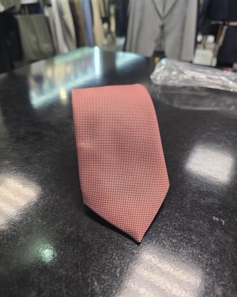 Viento powder pink textured tie, rolled view on dark counter
