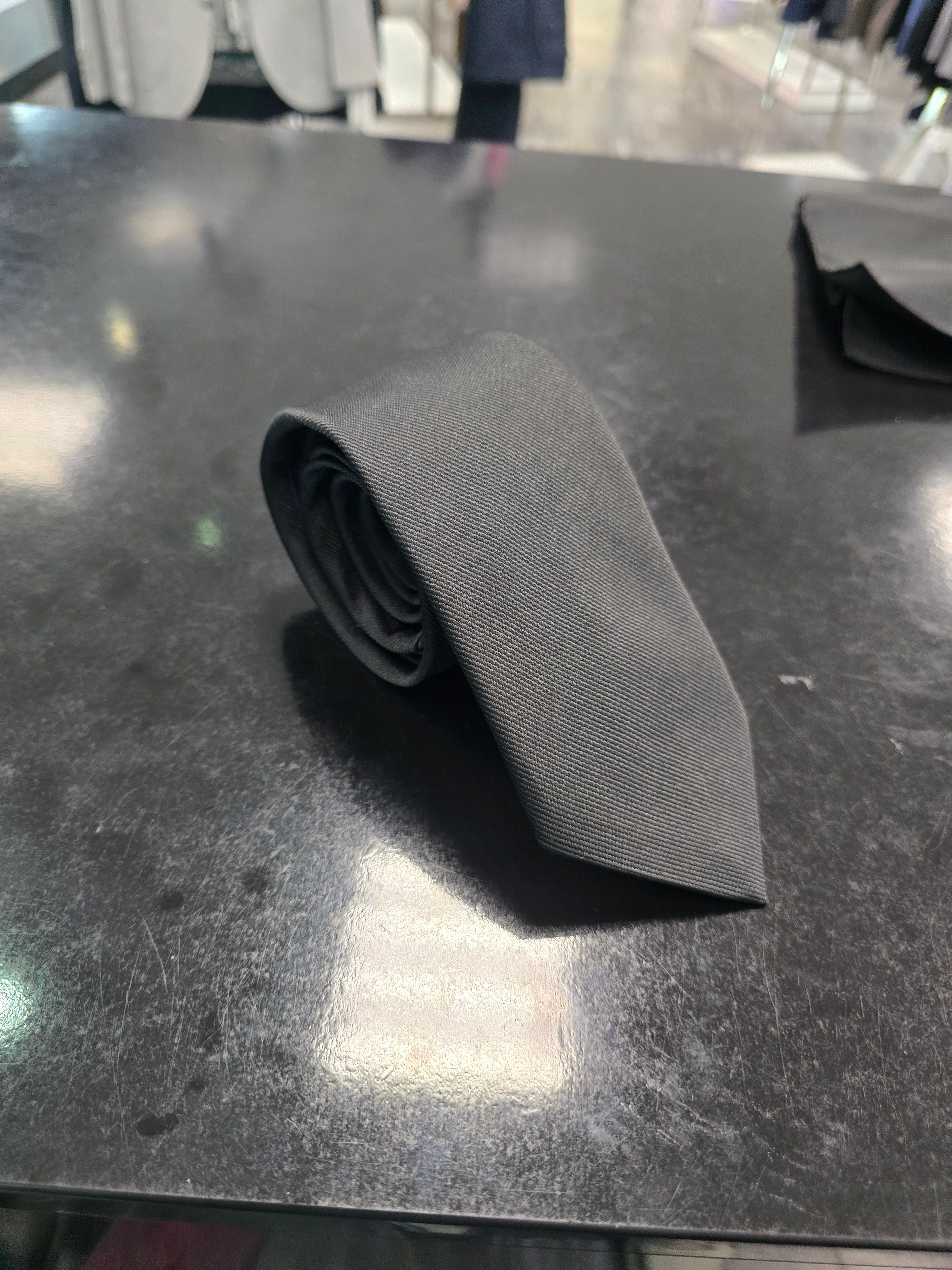Viento black twill tie, rolled view on dark counter