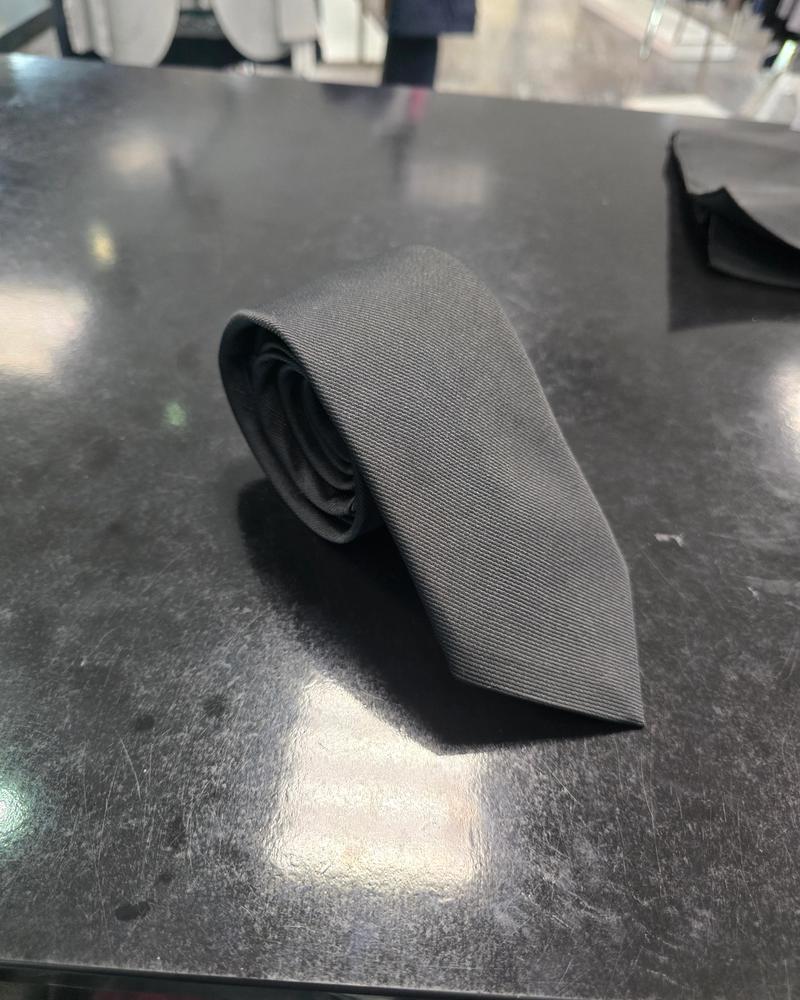 Viento black twill tie, rolled view on dark counter