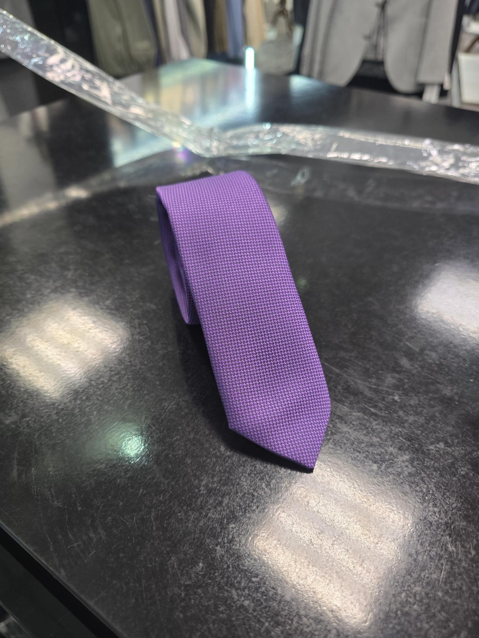 Viento textured purple tie, coiled view on dark counter