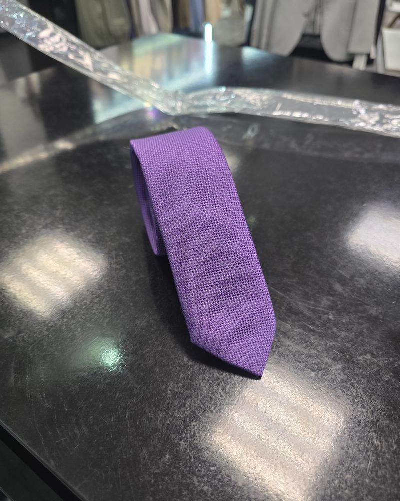 Viento textured purple tie, coiled view on dark counter