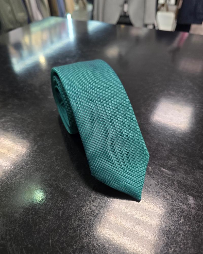 Viento textured teal green tie, rolled view on dark counter