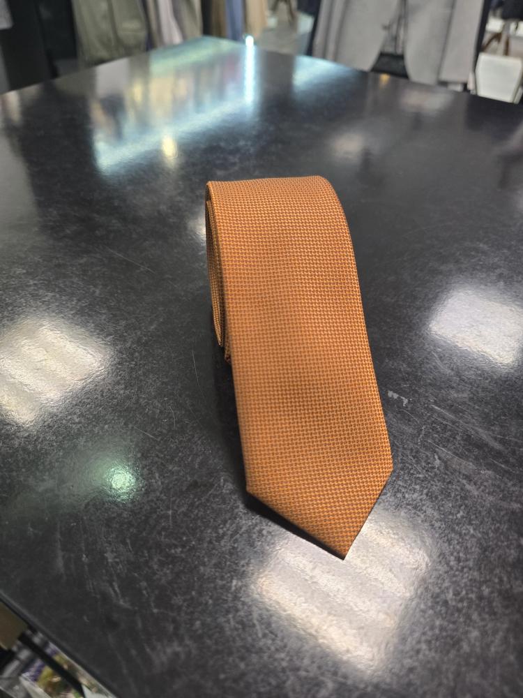 Viento textured burnt orange tie, rolled view on dark counter