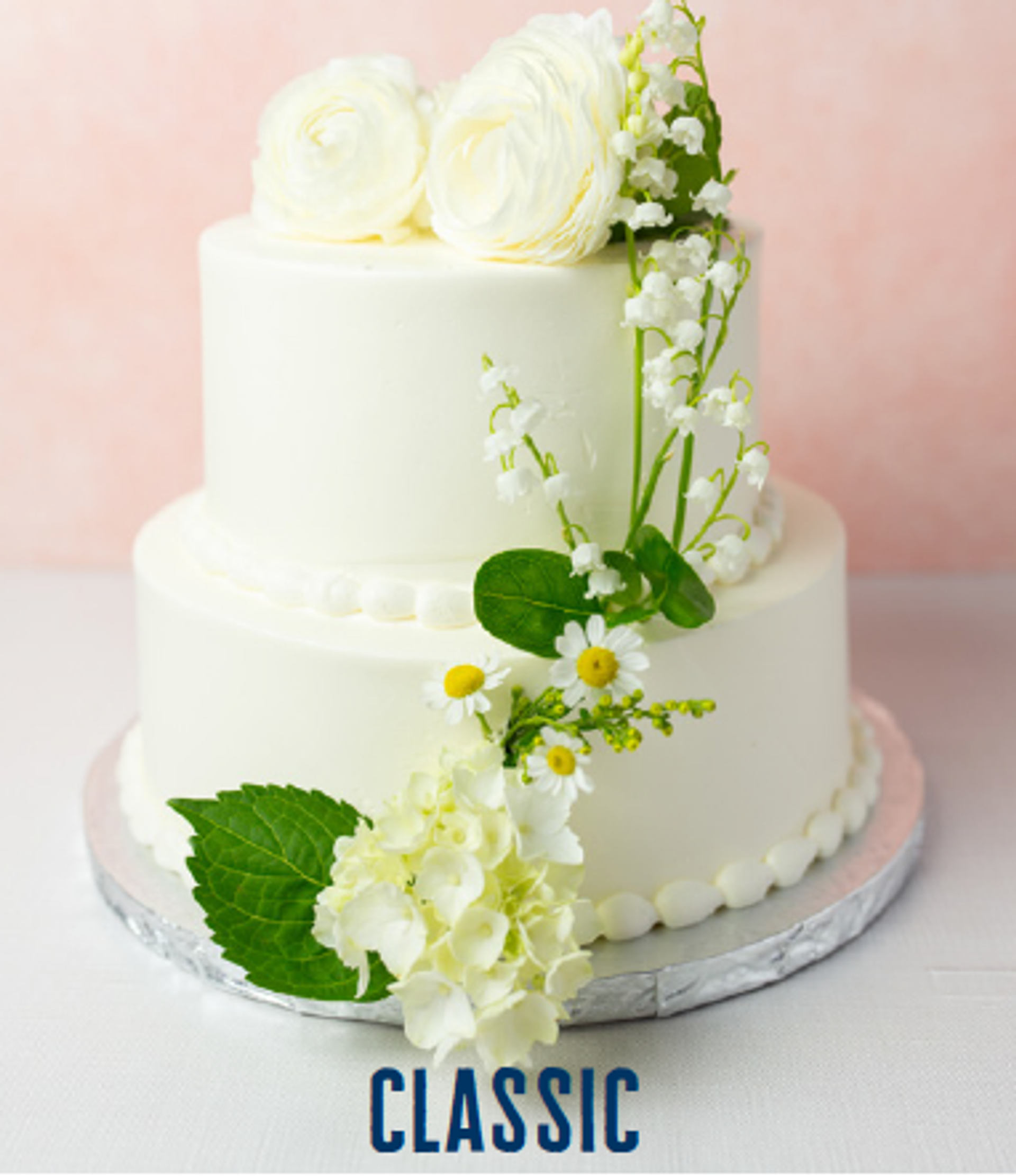 two tier wedding cake featuring classic buttercream design and fresh flowers