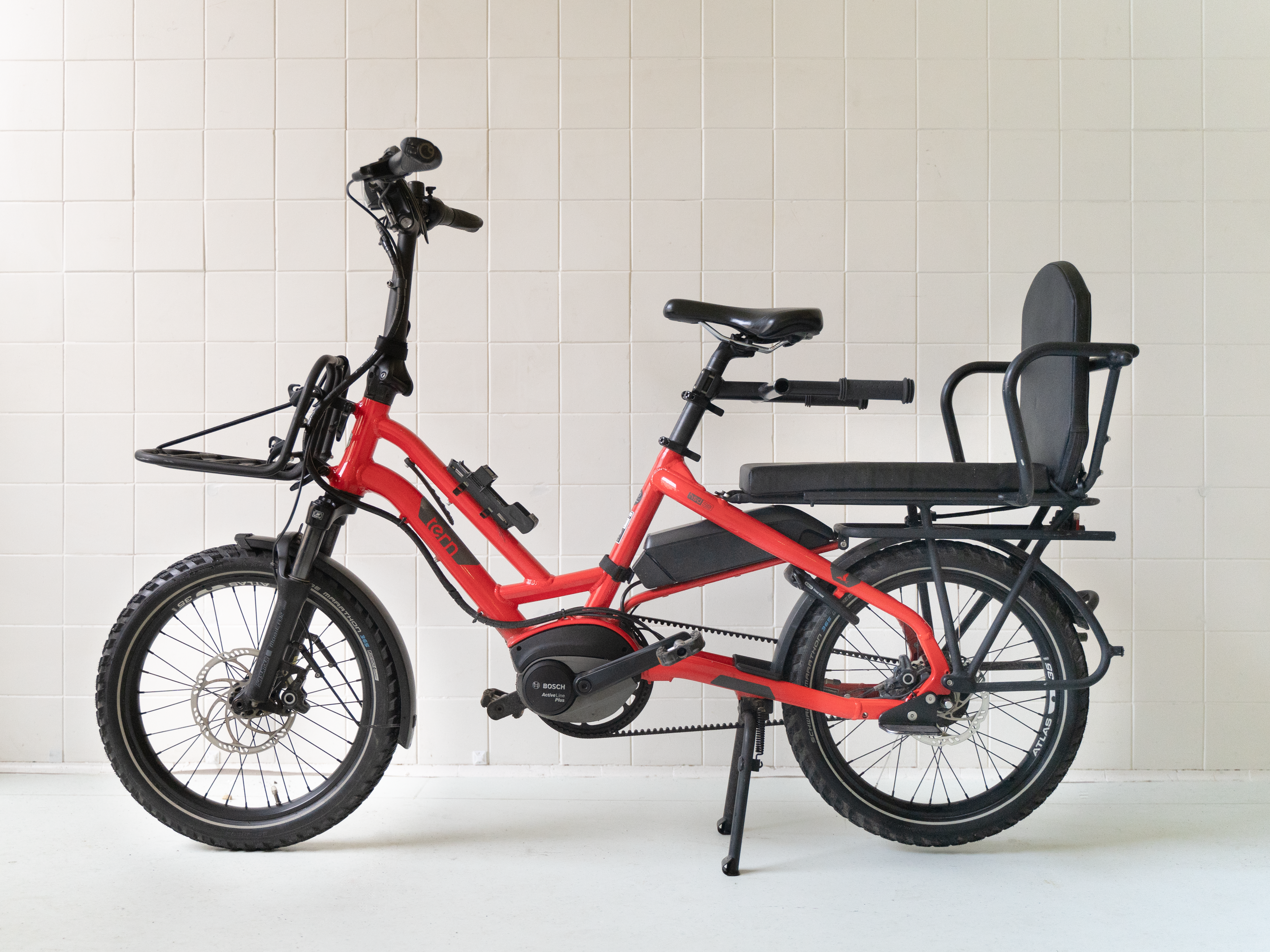 Bildet er av en rød Elsykkel som heter Tern HSD. Det er en liten sykkel med 20' hjul og plass til en stor passasjer