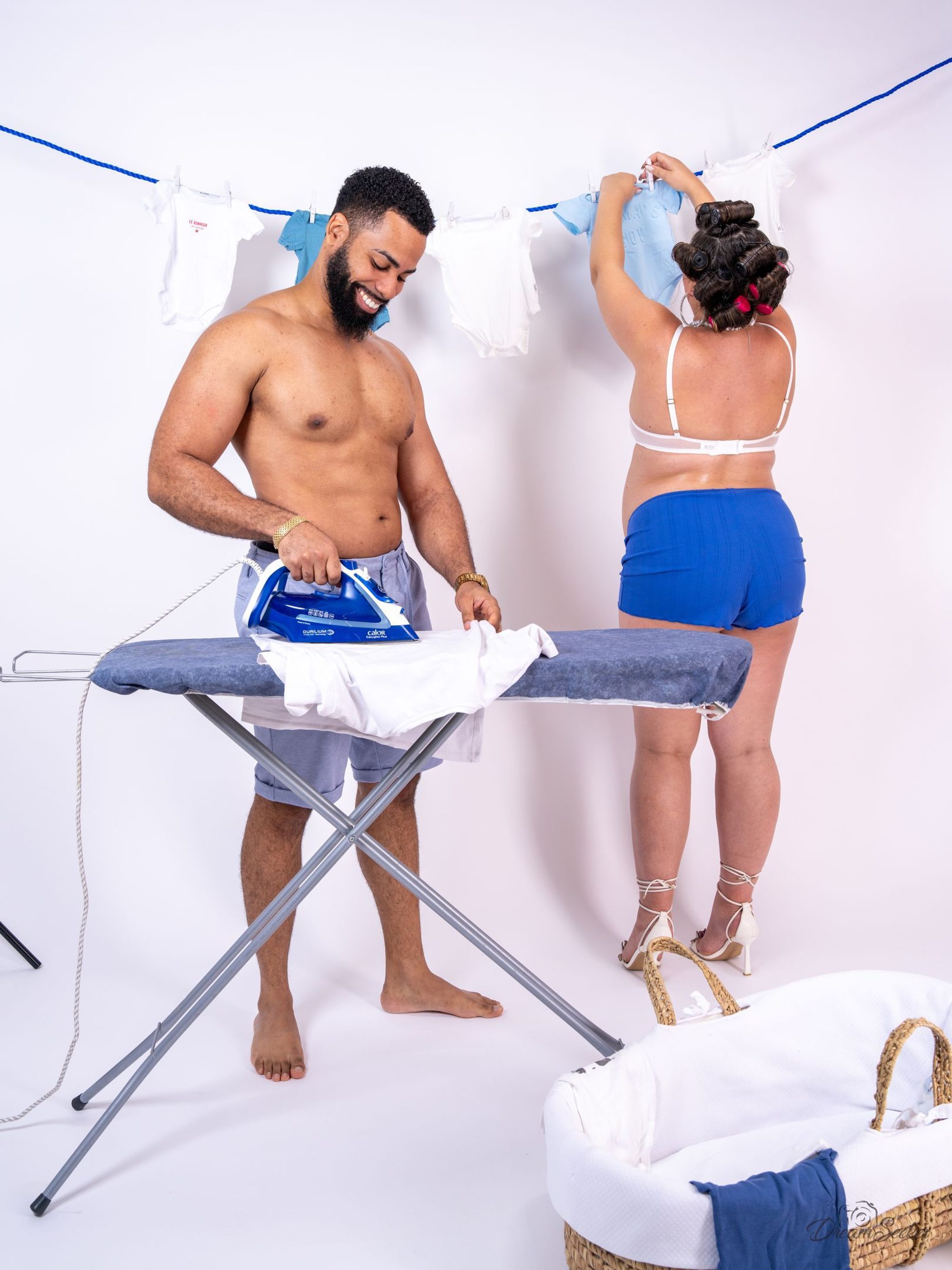 Futur père repassant pendant que sa compagne étend le linge de bébé