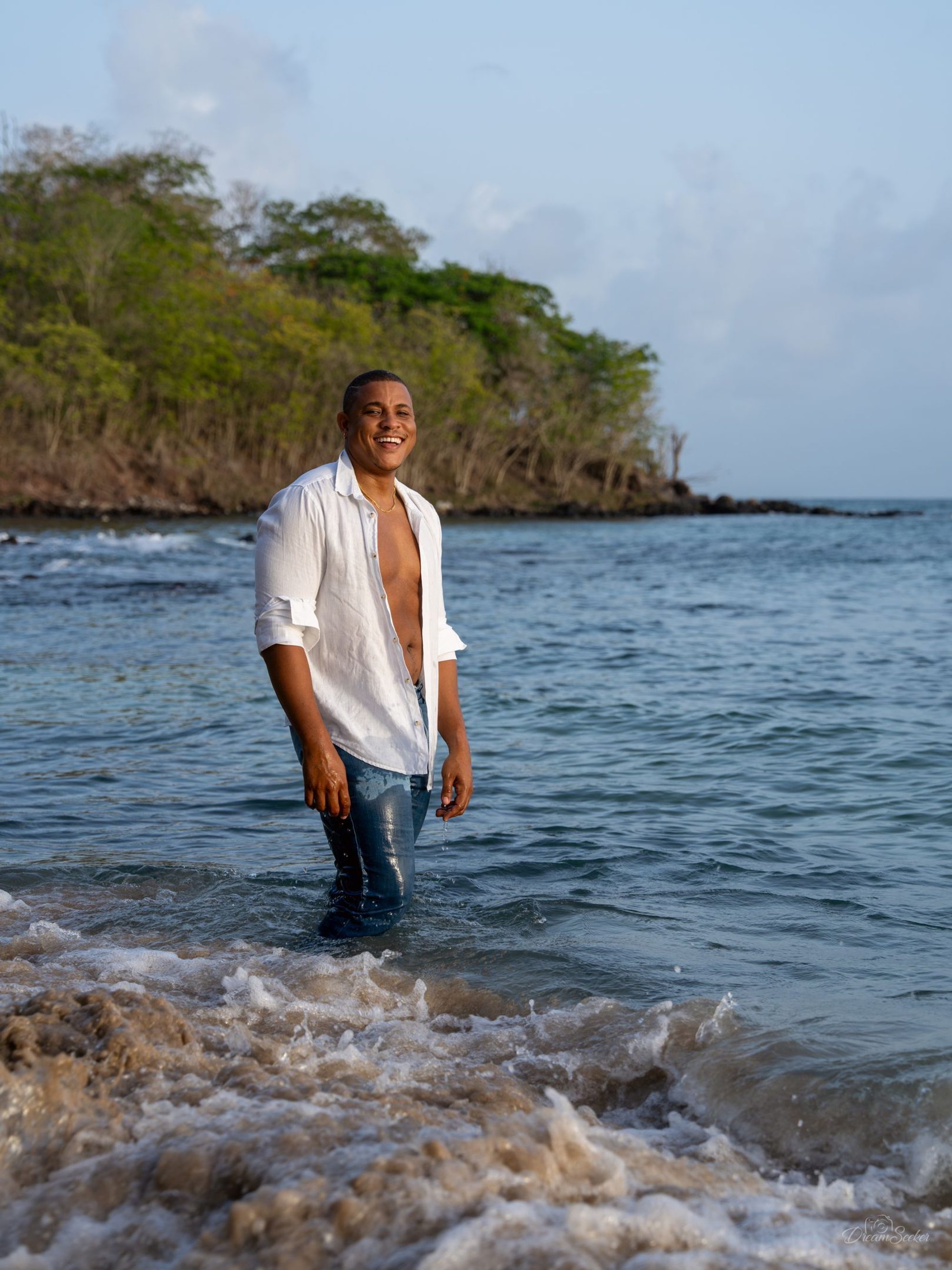 Homme en chemise blanche debout dans les vagues
