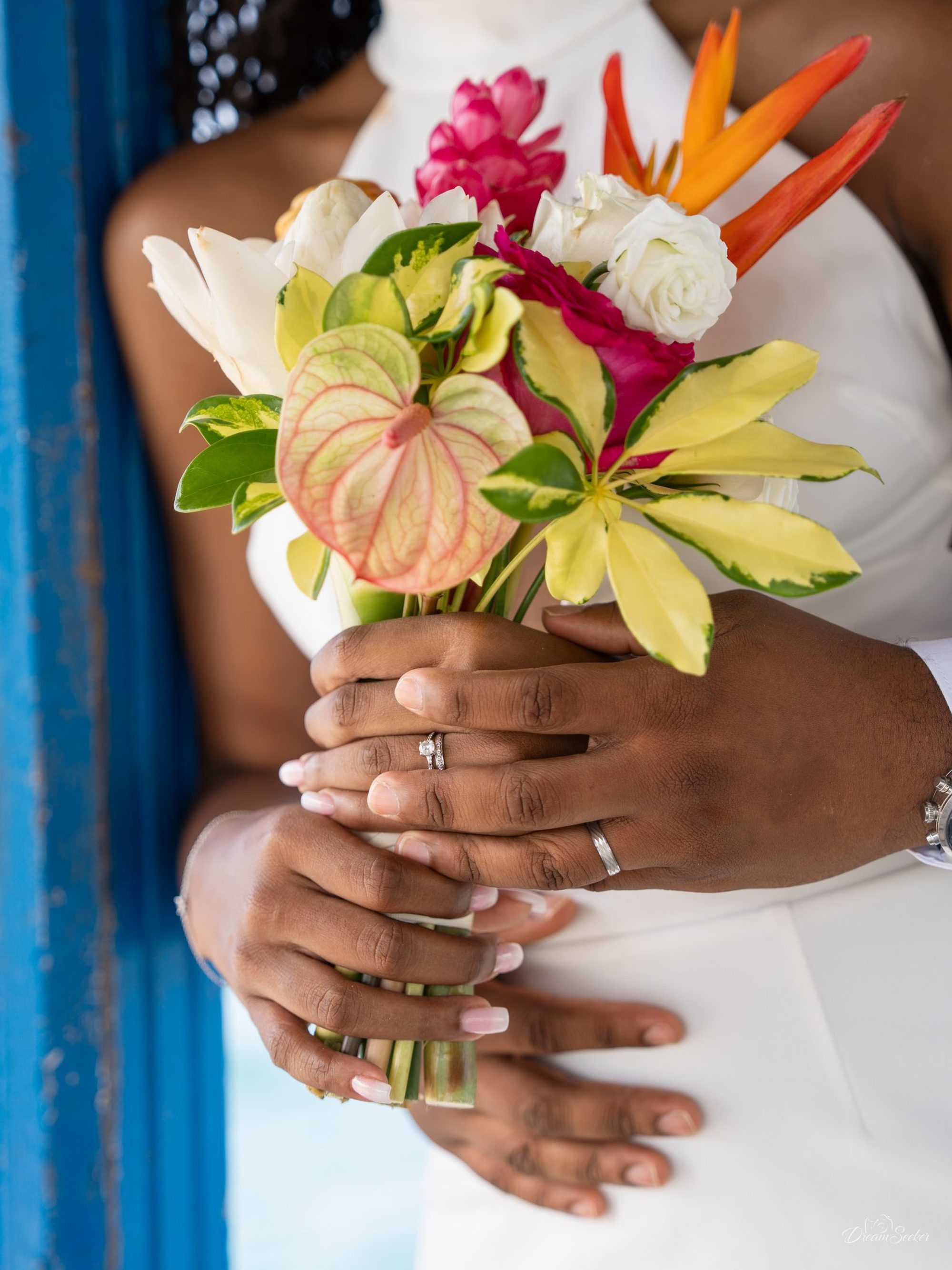 Mains de la mariée tenant un bouquet tropical, alliance au doigt