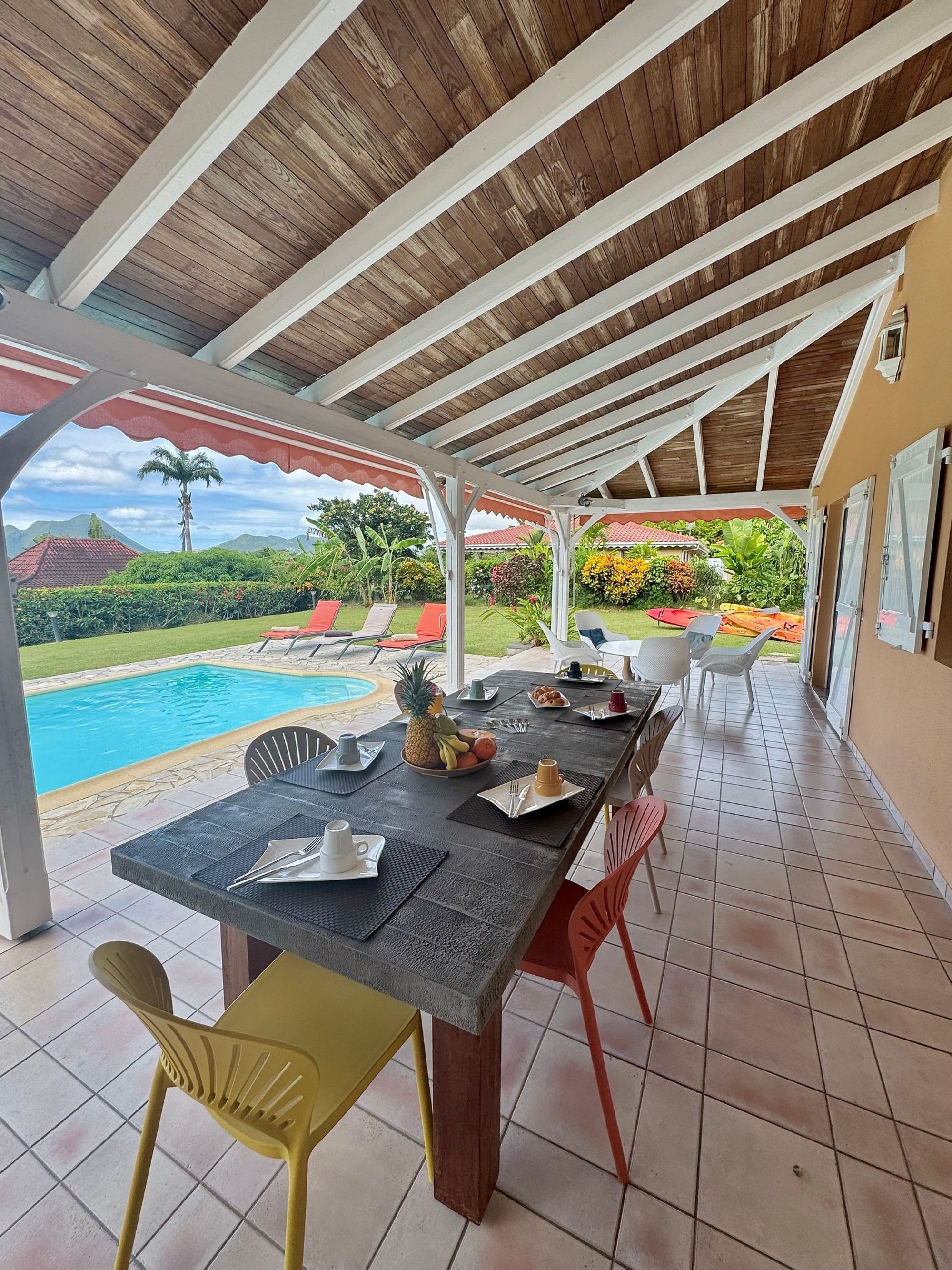 Terrasse couverte avec table et piscine, vue sur la mer