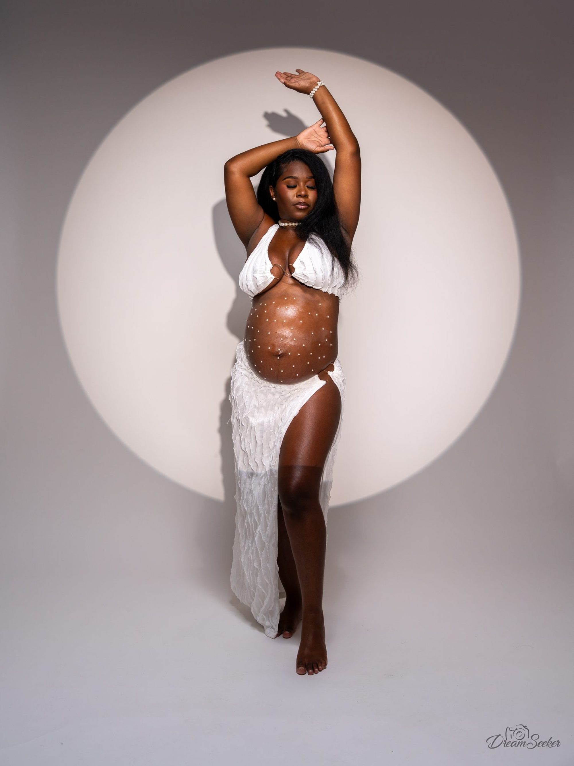 Future mère en studio, bras levés