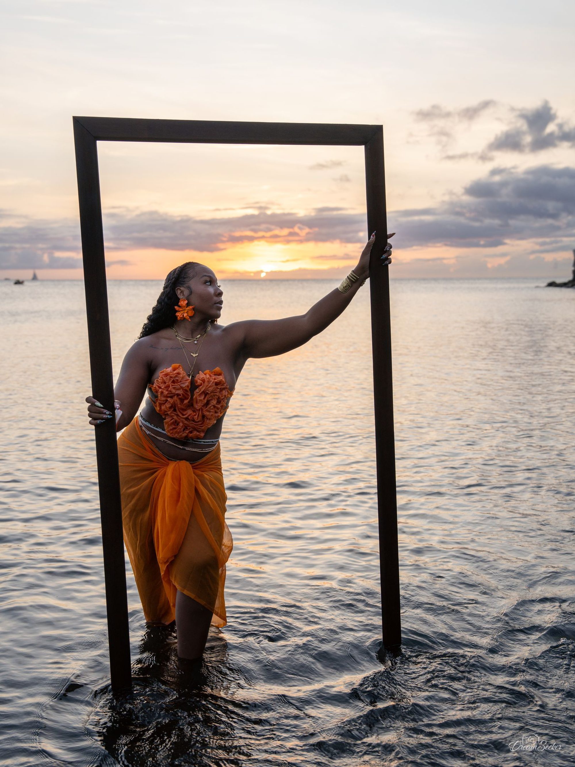 Femme en orange dans un cadre de bois posé dans la mer