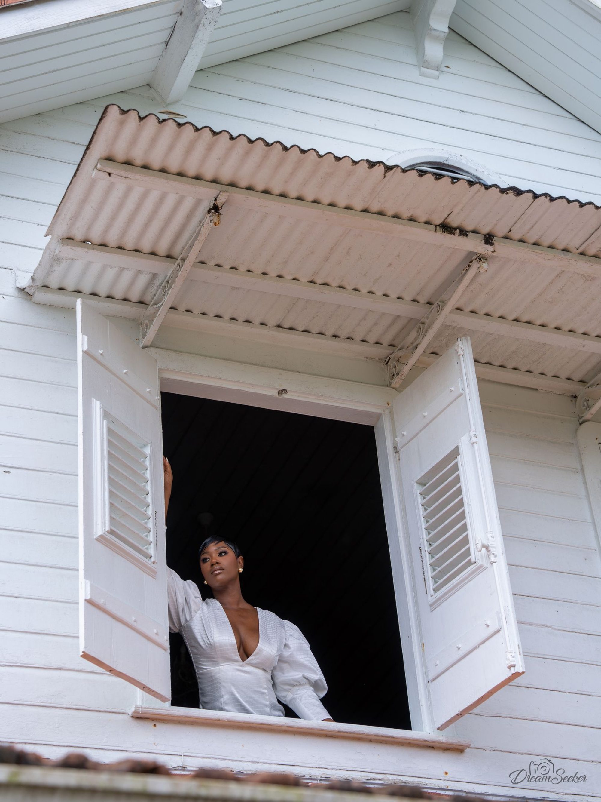 Femme en blanc à la fenêtre d’une maison créole