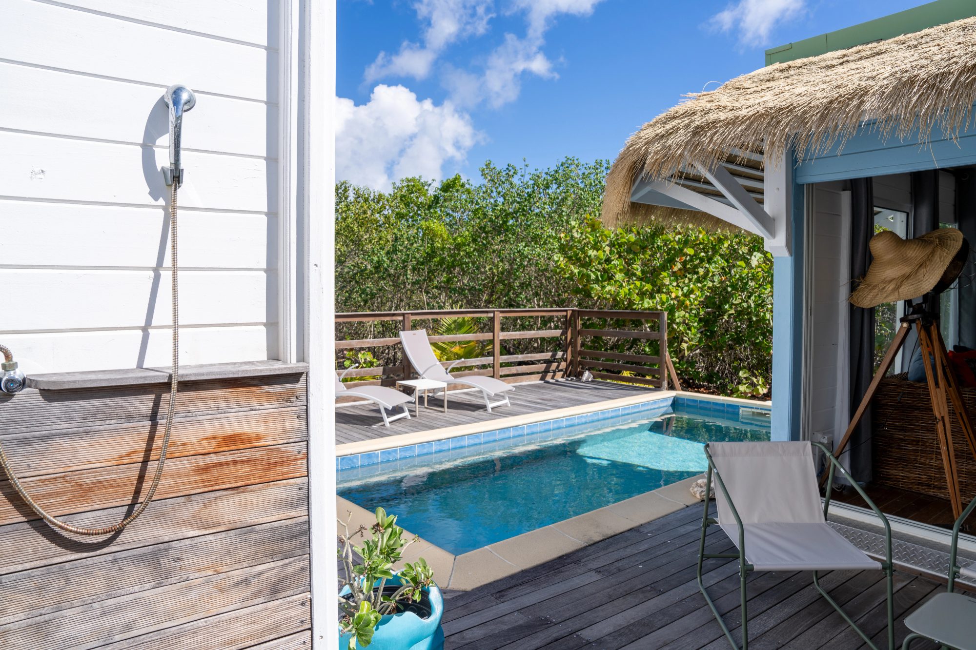 Villa tropicale avec piscine privée, terrasse en bois et toit en chaume sous un ciel bleu à Saint-Martin.