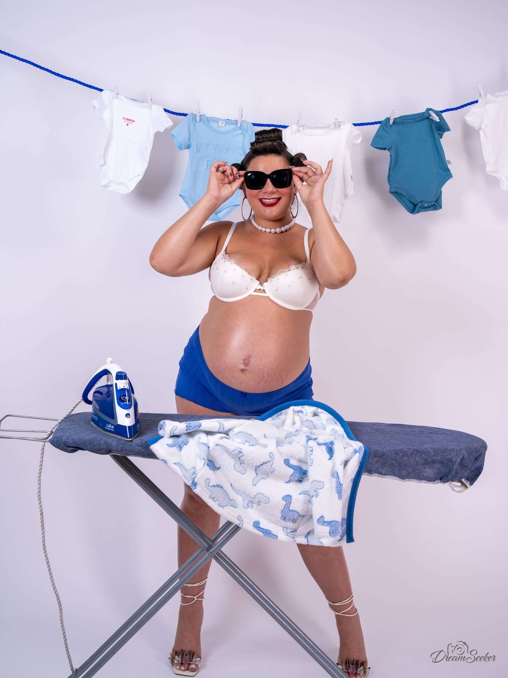 Future mère en lunettes de soleil devant une corde à linge de bébé