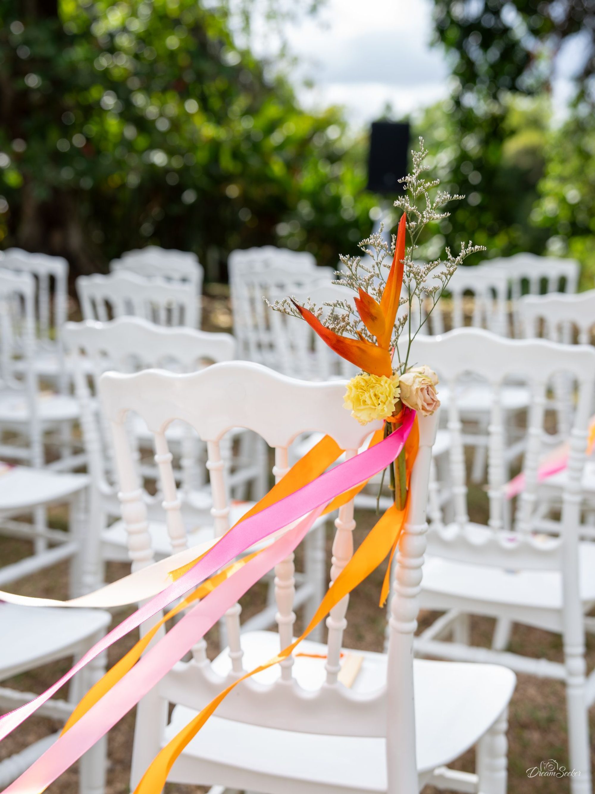 Chaises blanches décorées de rubans orange et rose