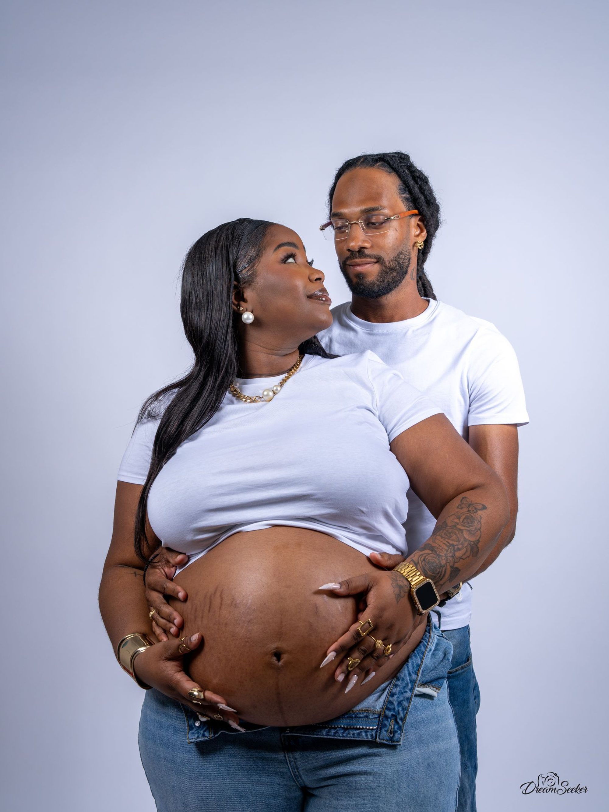 Couple en studio, les mains posées ensemble sur le ventre