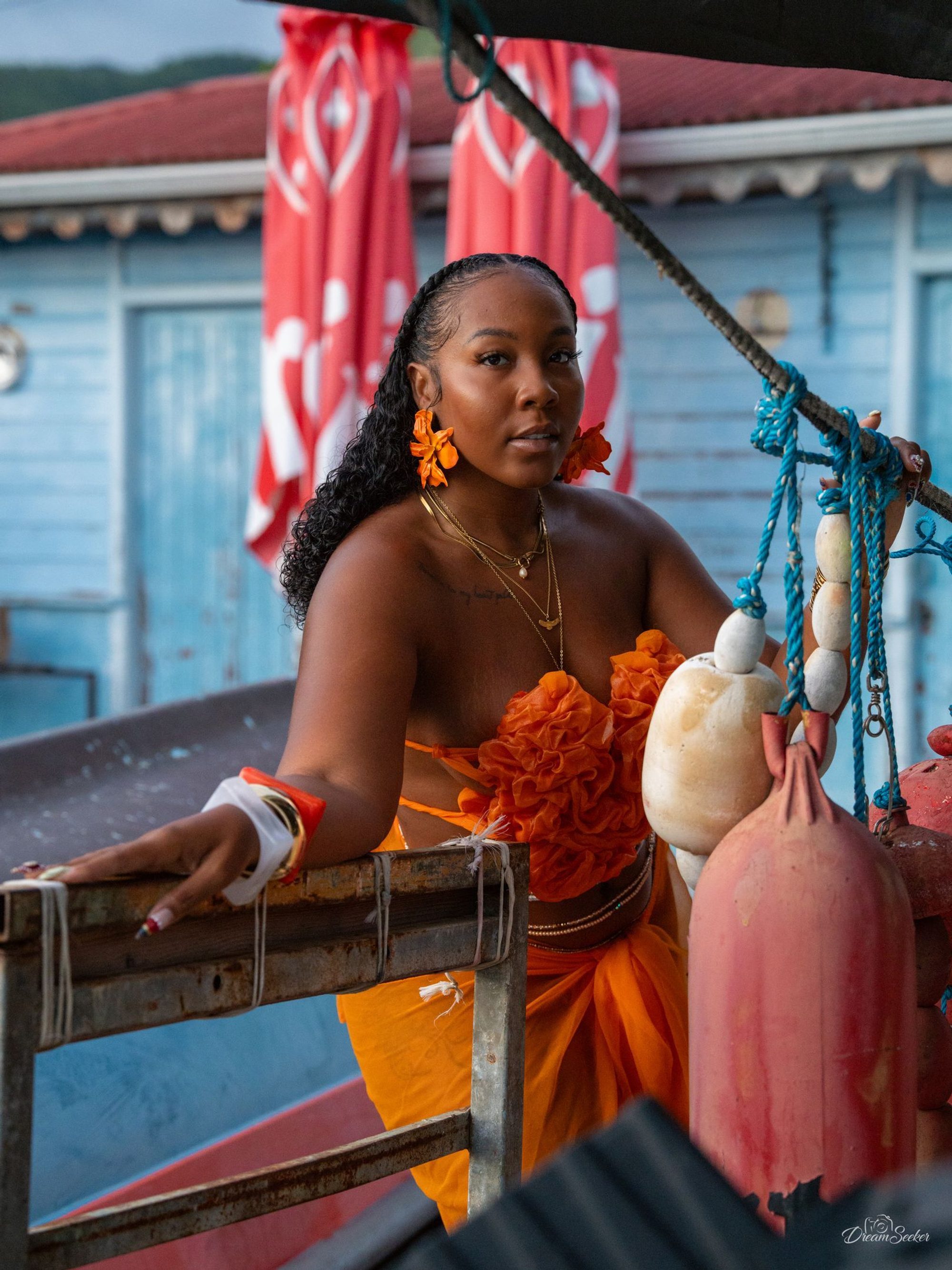 Femme en orange accoudée à une barque colorée