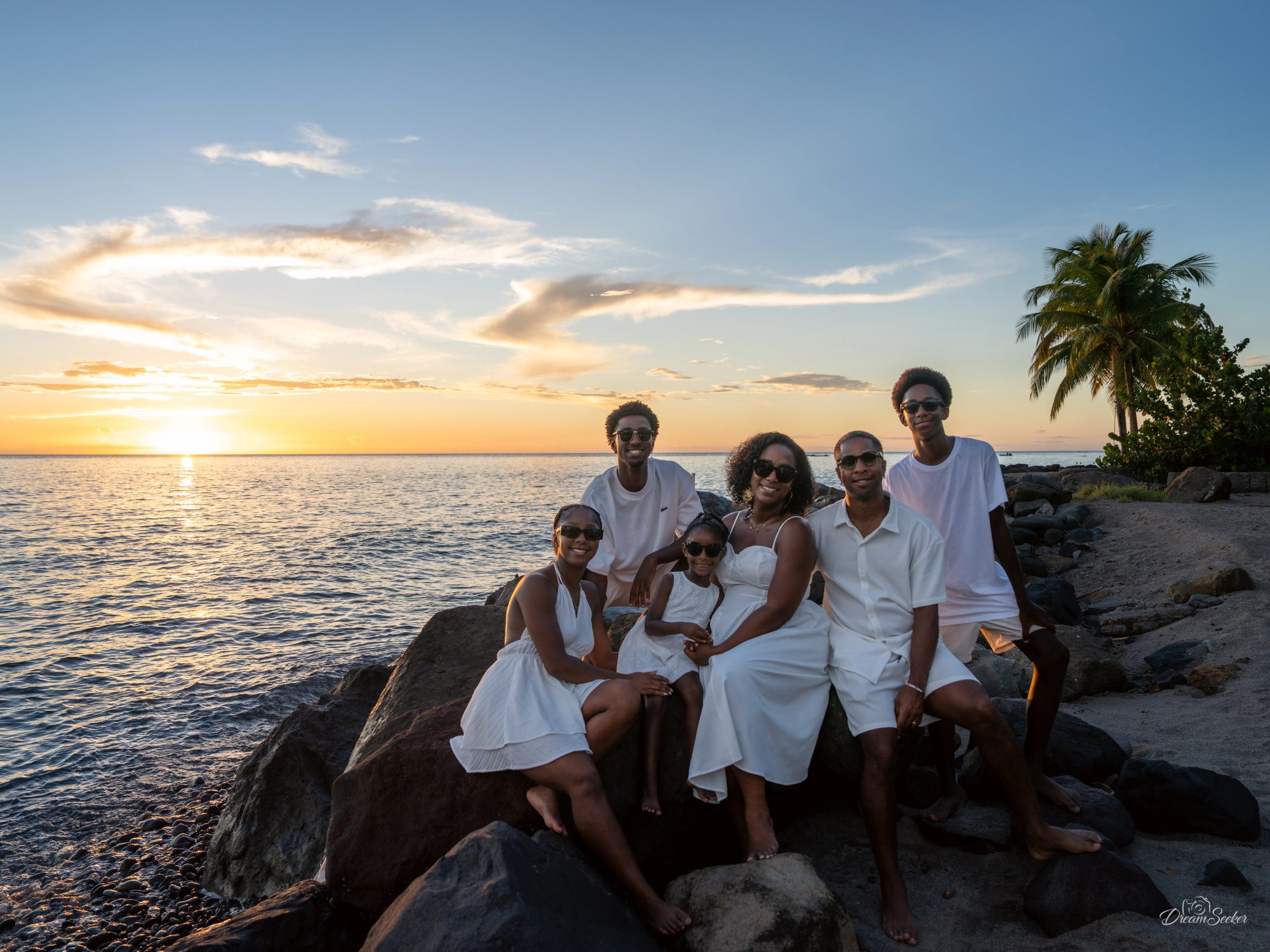 Famille en blanc sur des rochers au coucher du soleil