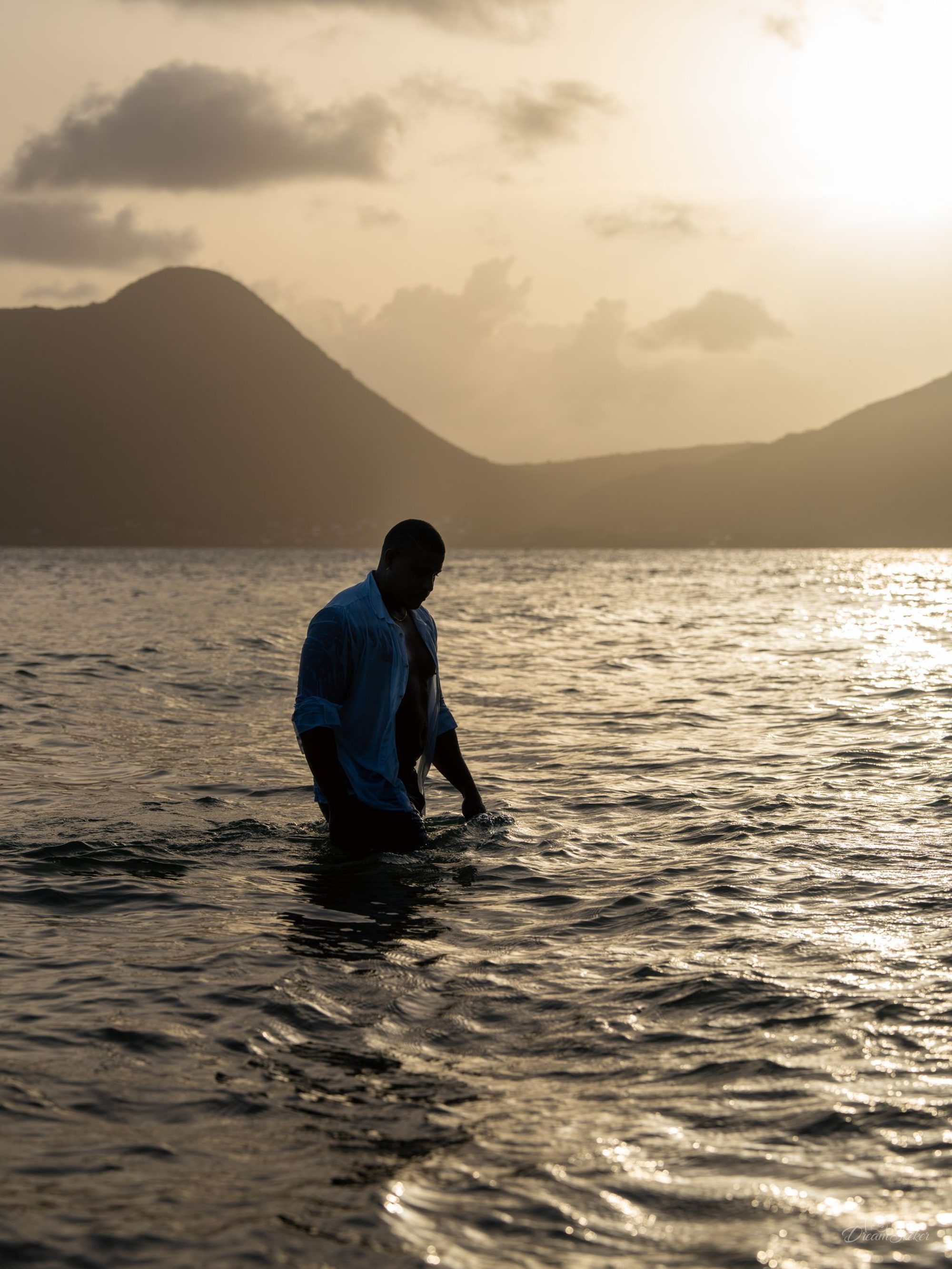 Silhouette d’un homme dans l’eau, montagne au loin