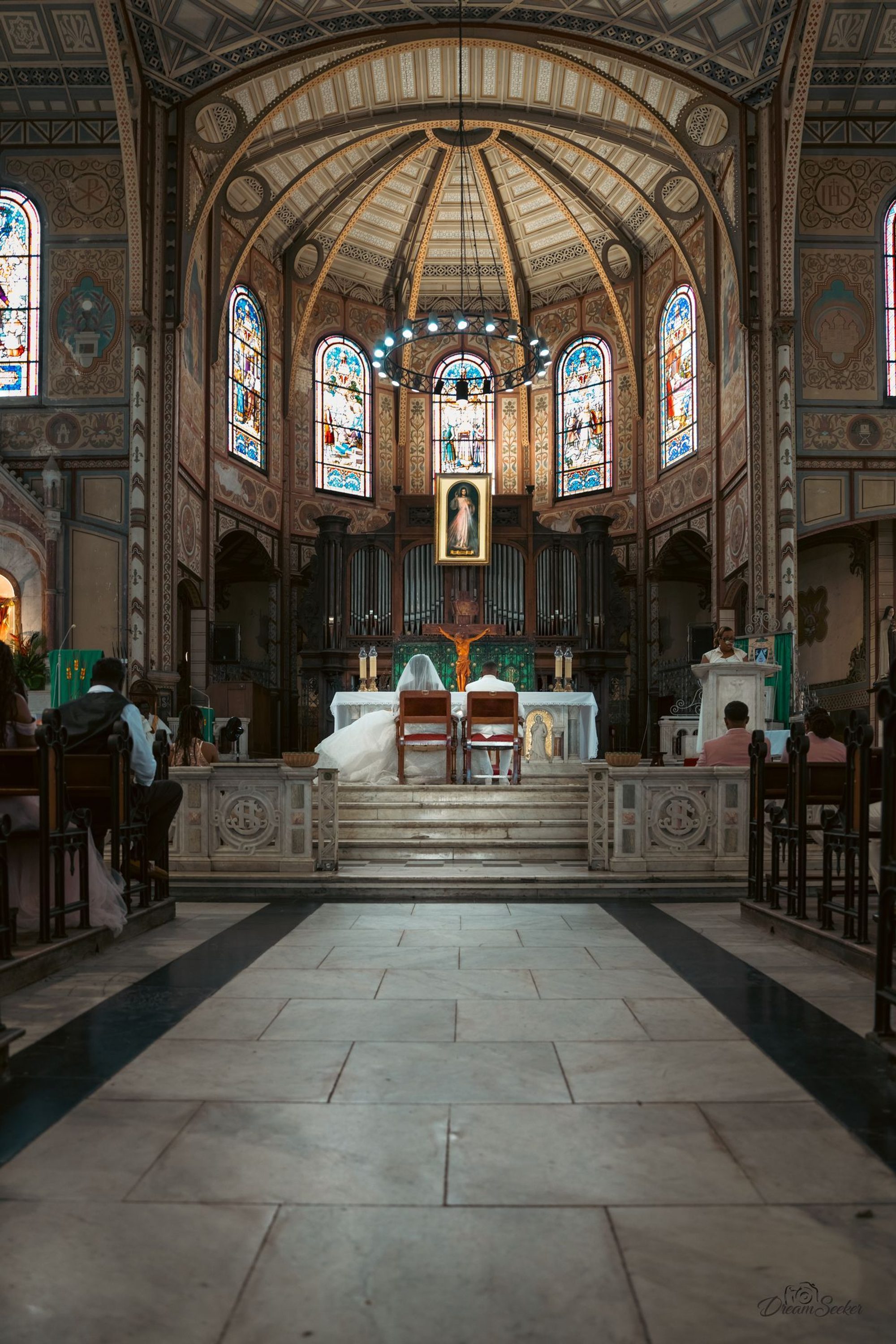Mariés à l’autel au fond d’une église aux vitraux colorés