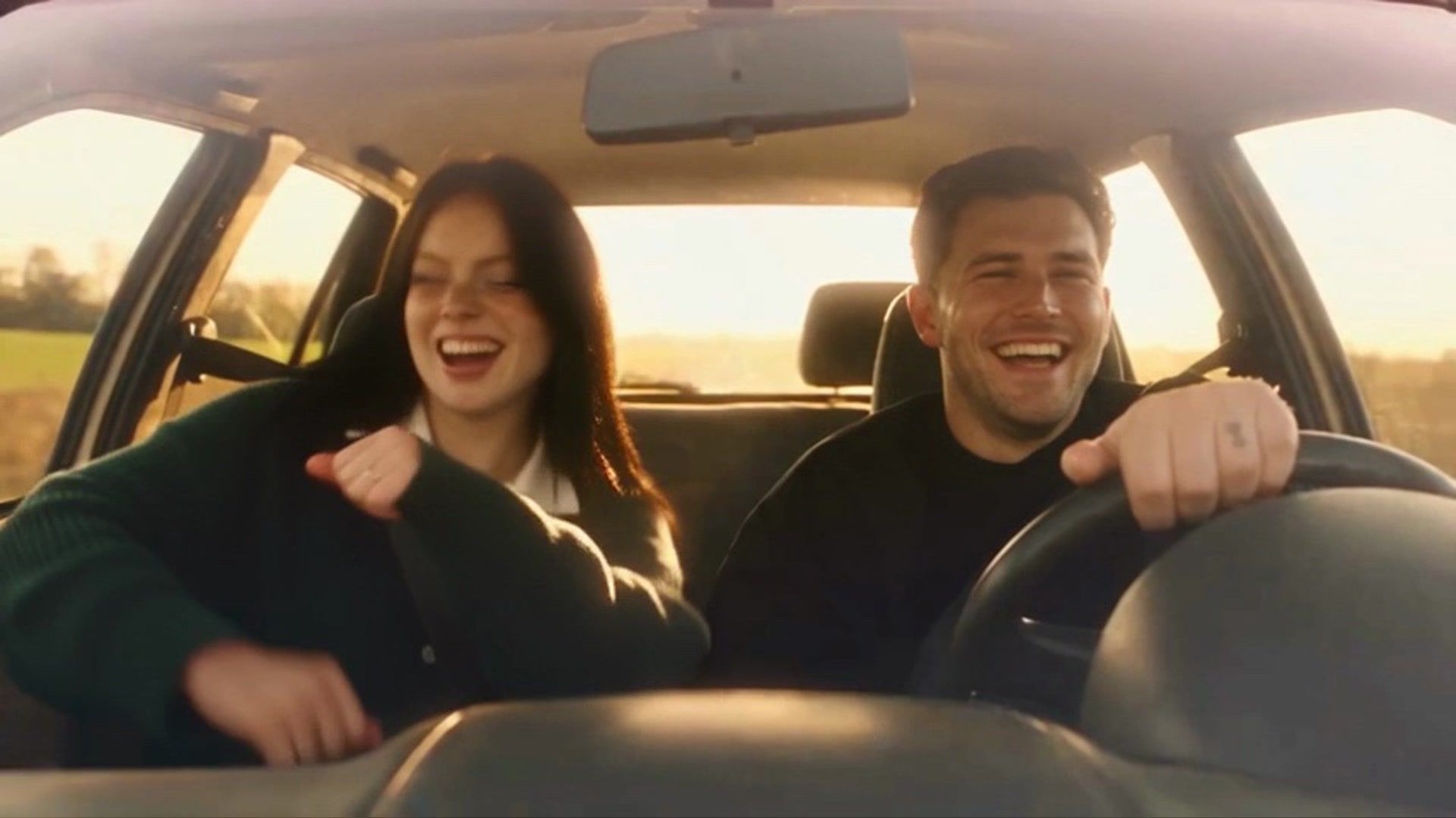 adult couple laughing together inside a car at sunset