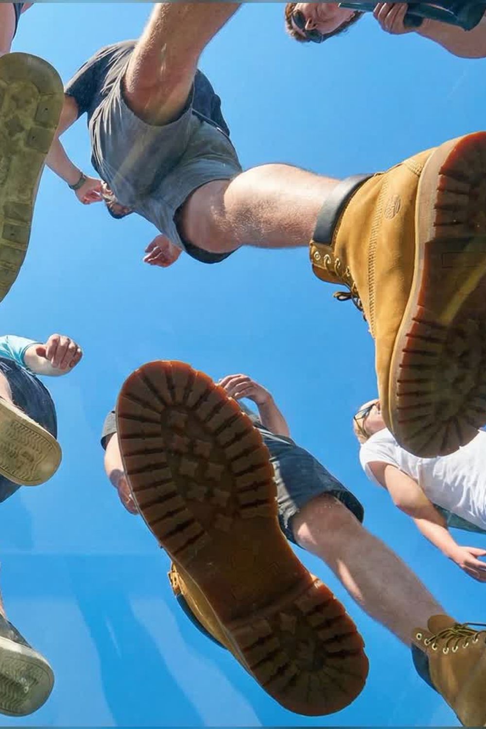 Low-angle imageat-owned video example of people walking over a camera under a blue sky