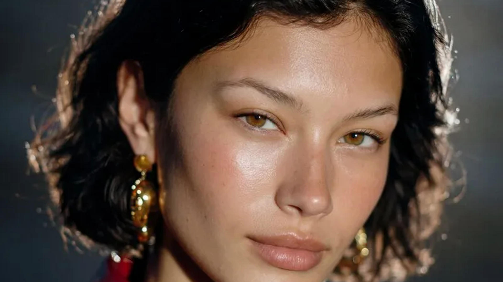 close fashion editorial portrait with gold earrings and dramatic studio lighting