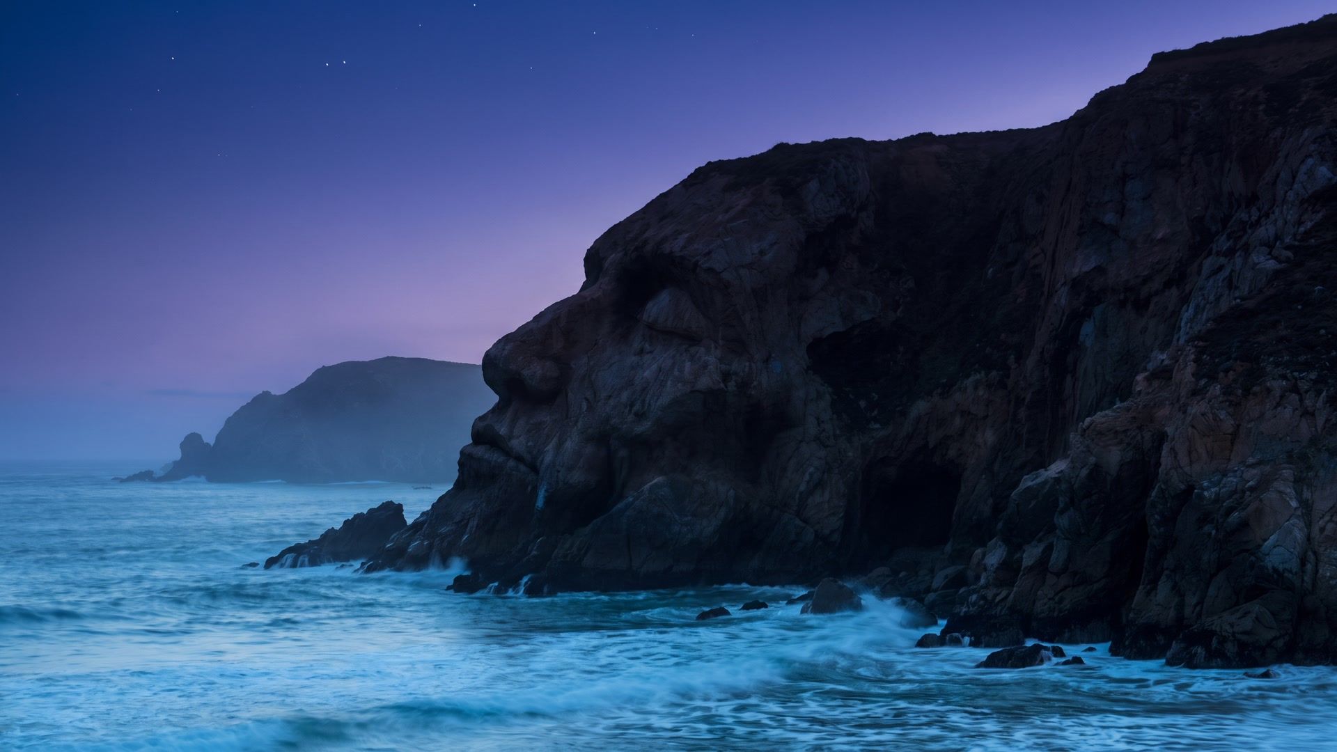 coastal cliff whose silhouette resembles a sleeping face at twilight
