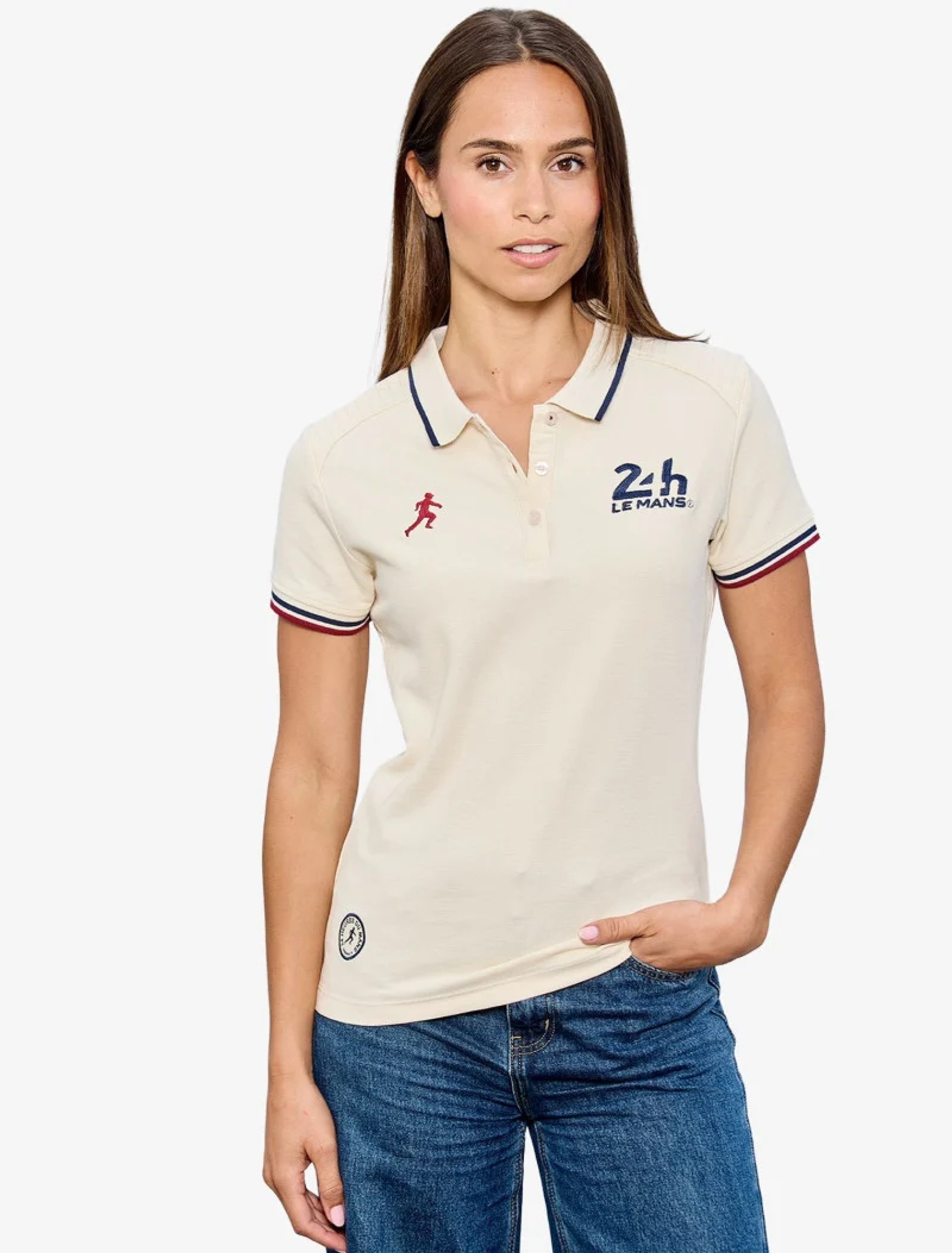 Femme portant un polo écru à liserés tricolores et logos 24h Le Mans, avec un jean bleu