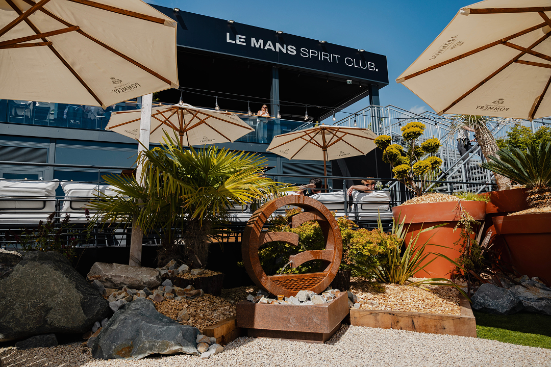 Terrasse du Le Mans Spirit Club avec parasols, salon extérieur et jardin paysager