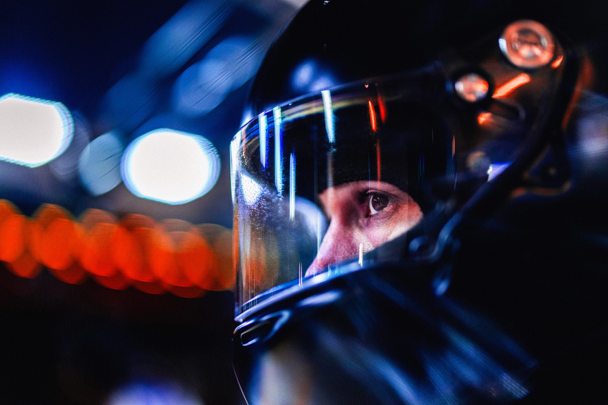Regard d’un pilote derrière la visière de son casque, éclairé par des lumières bleues et rouges