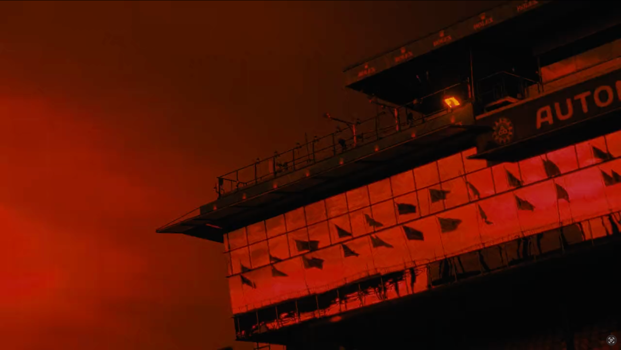 Tour de contrôle du circuit éclairée en rouge sous un ciel sombre