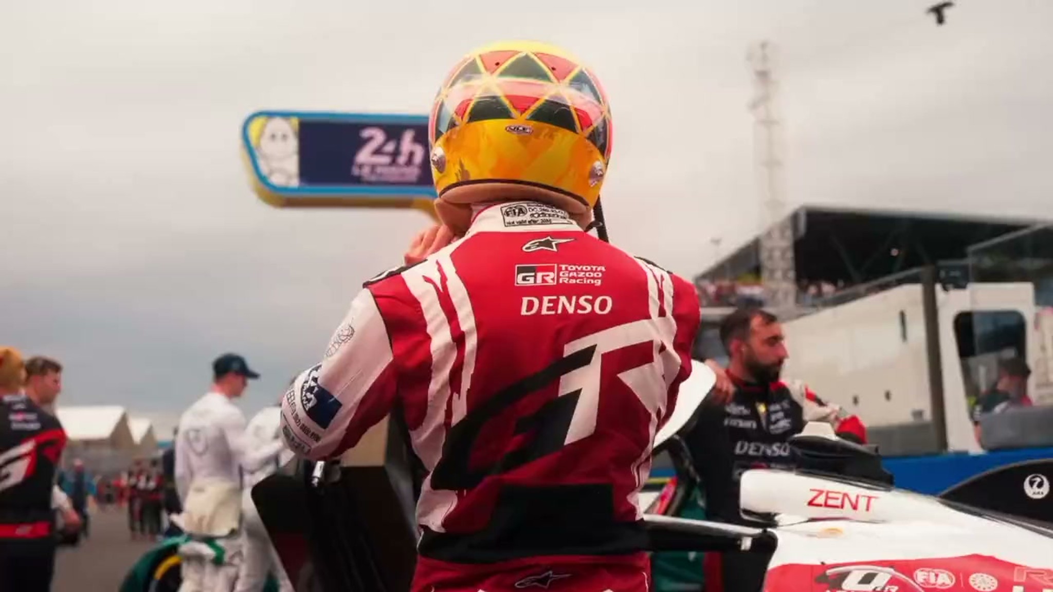 Pilote Toyota Gazoo Racing casqué, vu de dos près de sa voiture dans la voie des stands des 24 Heures du Mans