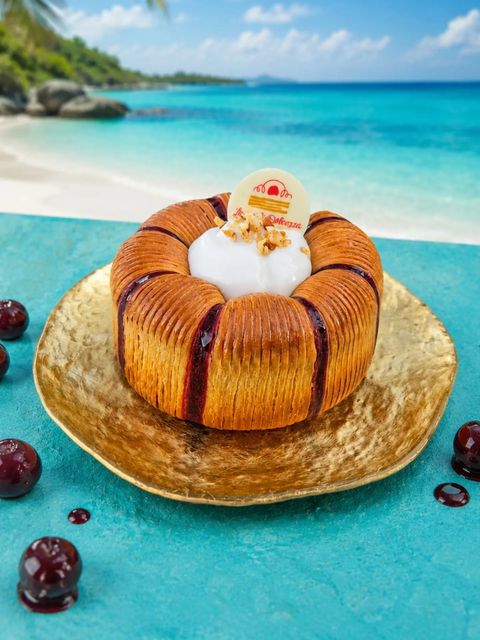 Amaréa Un'ondata tropicale dal cuore di amarena Crown di impasto sfogliato al cocco, ripiena di molleux alla…