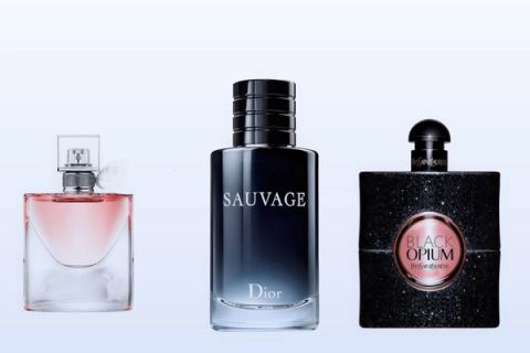 Three fragrance bottles, La Vie Est Belle, Sauvage and Black Opium, on a pale blue background