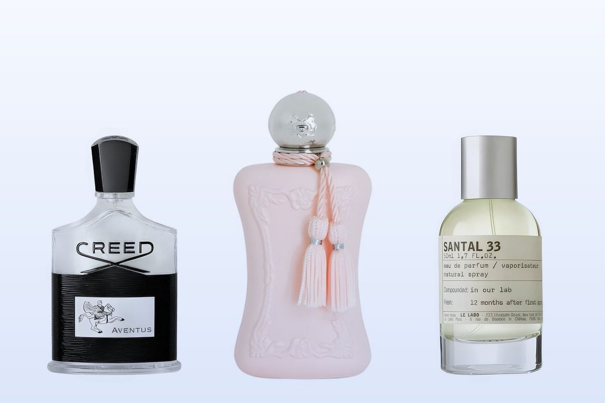 Three fragrance bottles, Aventus by Creed, Delina by Parfums de Marly and Santal 33 by Le Labo, on a pale blue background
