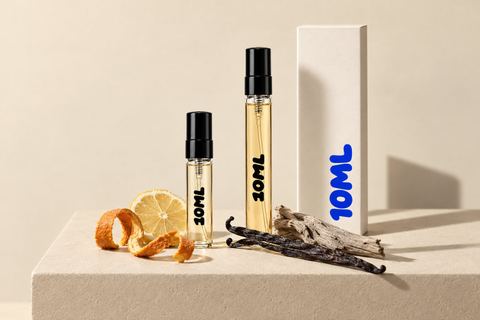 Een 10ML-decant van 3ml naast een 10ML-decant van 10ml, met citrusschil, vanillestokjes en een stuk hout ervoor