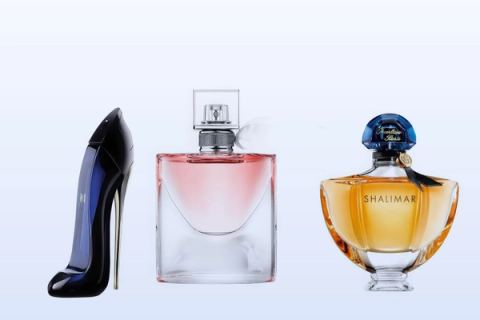 Három parfümösüveg, a Good Girl, a La Vie Est Belle és a Shalimar Eau de Parfum, halványkék háttér előtt