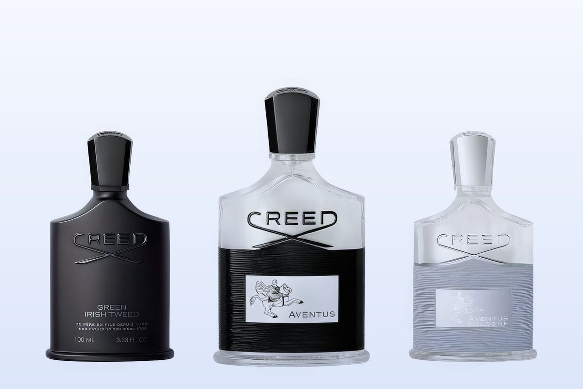 Drie Creed-flacons, Green Irish Tweed, Aventus en Aventus Cologne, op een lichtblauwe achtergrond
