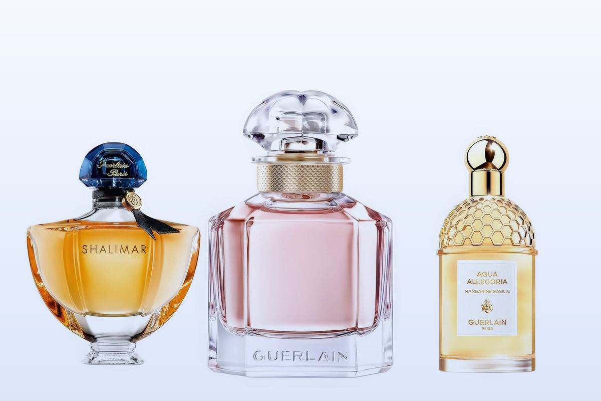 Three Guerlain bottles, Shalimar Eau de Parfum, Mon Guerlain and Aqua Allegoria Mandarine Basilic, on a pale blue background